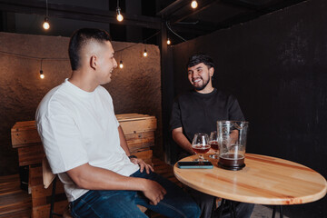 friends talking and laughing at a bar table with beer at night