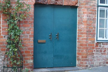 close-up of a stylish pretty new green double-leaf door with golden letterbox slot in an old building