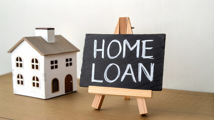 Miniature white house and Home Loan chalkboard sign, wooden desk, financial mortgage concept