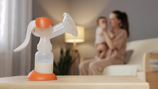 A mother enjoys precious moments with her baby while a breast pump rests on the table. The cozy living room is filled with soft light and a calming atmosphere, perfect for nurturing