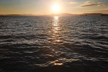 Fototapeta premium Sunset over dark water. Vibrant colors over the ocean horizon. Peaceful waves and golden sunlight reflecting on the water. Serene coastal landscape. Travel and relaxation. Scary power of the sea.