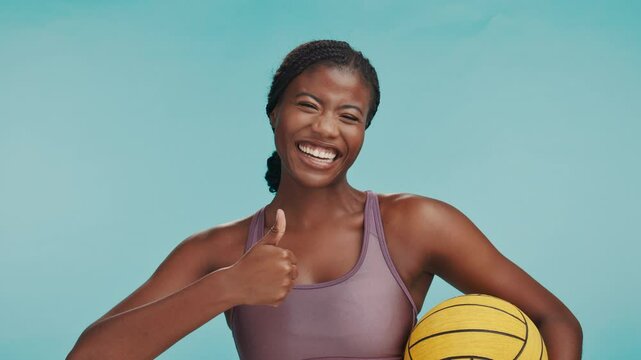 Sports, thumbs up and face of black woman in studio with smile, motivation and winning champion. Netball, yes and laughing athlete girl with ball, like hand sign and happy review on blue background