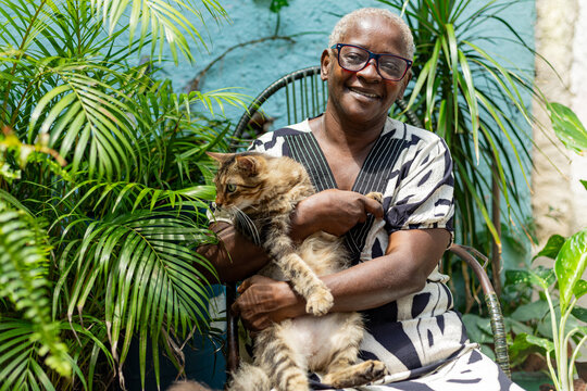 Happy elderly black woman with her pet on her lap. Dog, cat, animal. Rio de Janeiro, Brazil.