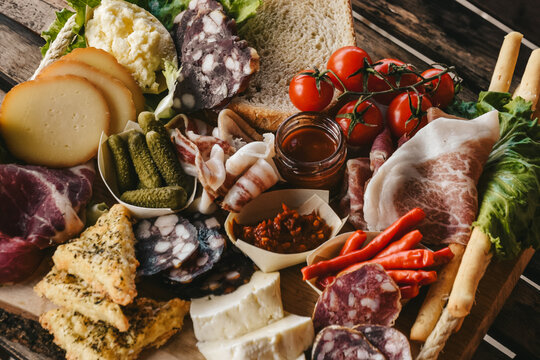 Traditional italian appetizers (antipasto). charcuterie board. Salami, prosciutto, cheese, sticks of bread and vegetables served on the wooden board. Dinner or aperetif party concept.