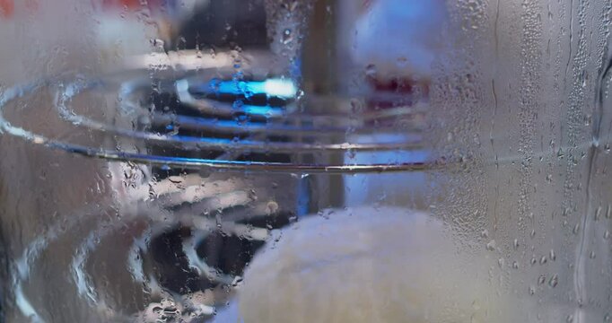 Chinese national dish made from pigodi dough is cooked in a glass rotating steamer. Cooking process. Close-up.