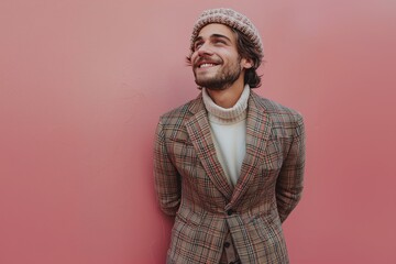 Smiling man in plaid blazer and beanie hat against pink background, cheerful fashion portrait with playful expression, casual modern menswear editorial with copy space
