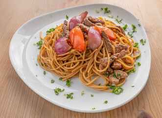 tallarin saltado traditional Peruvian dish with noodles, pork and sauteed vegetables 
