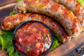 Grilled sausages served with fresh salsa on a wooden table
