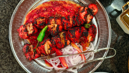 BBQ Chicken Tikka with fresh onion, tomatoes and green chilies in a platter. Chicken Sheesh Tauk