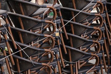 Plastic stacking commercial brown armchairs in rows tied and locked outdoors