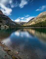 Naklejka premium Un hermoso lago en medio de las montañas, con cielo azul y nubes