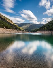 Obraz premium Un hermoso lago en medio de las montañas, con cielo azul y nubes