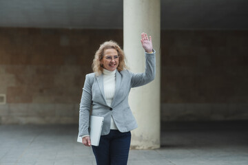 Confident businesswoman waving while walking outdoors