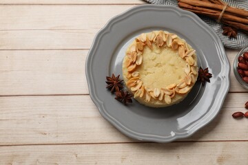 Delicious semolina halva with almond flakes and spices on white wooden table, flat lay. Space for text