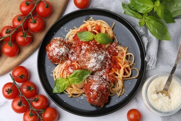 Delicious pasta with meatballs, basil, cheese and tomatoes on white table, flat lay