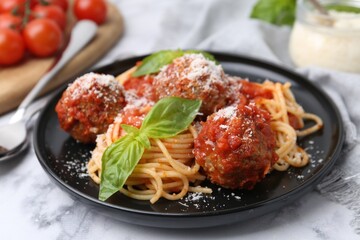 Delicious pasta with meatballs, basil and cheese on white marble table, closeup