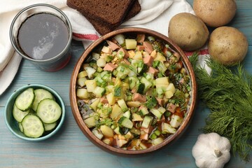 Delicious okroshka soup with kvass and ingredients on blue wooden table, flat lay