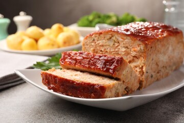 Delicious baked turkey meatloaf with vegetables served on grey table, closeup