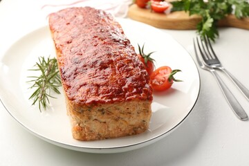 Delicious baked turkey meatloaf, rosemary, cherry tomatoes and parsley on white table, closeup