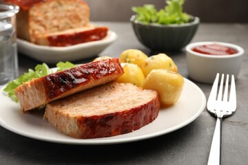 Delicious baked turkey meatloaf with potatoes served on grey table, closeup