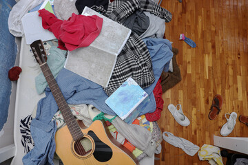 Scattered Shoes, Guitar and Clothes on Messy Teenage Girl's Room Floor and Bed.