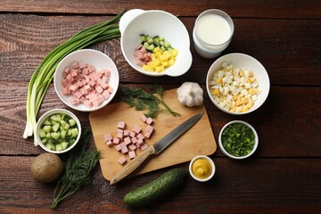 Cut ingredients for okroshka soup and knife on wooden table, flat lay