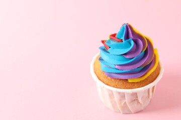 One delicious cupcake with colorful cream on pink background, closeup. Space for text