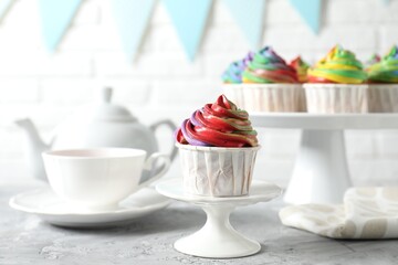 Delicious cupcake with colorful cream on grey textured table, closeup