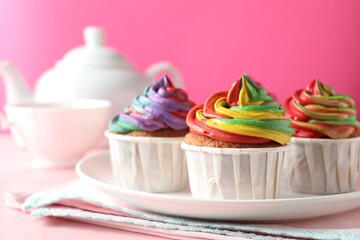 Delicious cupcakes with colorful cream and tea on pink table, closeup