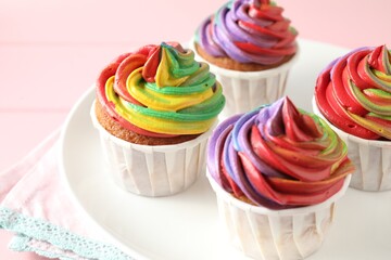 Delicious cupcakes with colorful cream on pink table, closeup