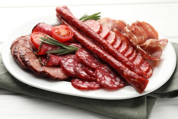 Different smoked sausages slices served on white wooden table, closeup