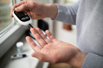Close-up Of A Man's Hand Checking Blood Sugar Level With Glucometer