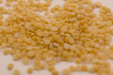 Close up of small yellow lentils spread on a surface with natural lighting