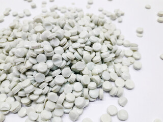 Greenish white plastic granules on a white background, recycled plastic waste ready to be used for re-production.