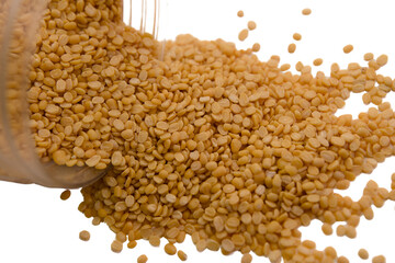 Golden seeds spilling from a container on a plain surface