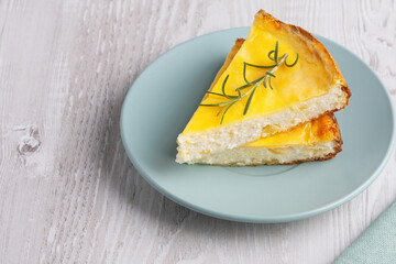 Delicious cottage cheese casserole served on a light blue plate with a sprig of rosemary accent