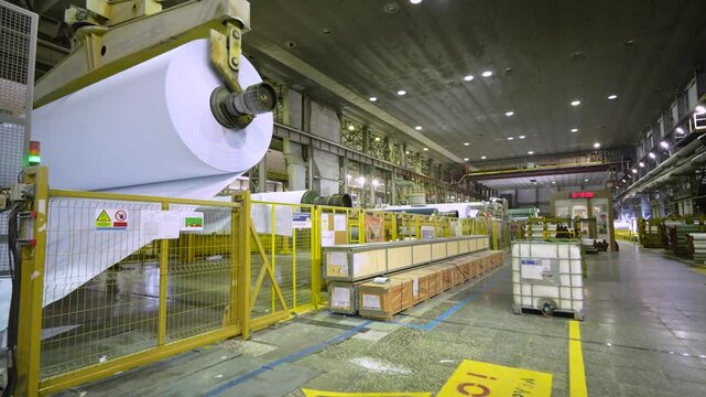 The crane operator unloads the finished paper in a roll from the paper machine. Paper production.