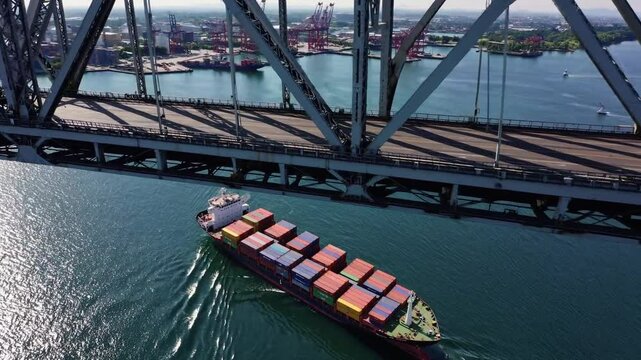 aerial view capturing the striking sight of a massive cargo ship gliding beneath a towering bridge, its deck loaded with colorful shipping containers arranged in precise rows. 
