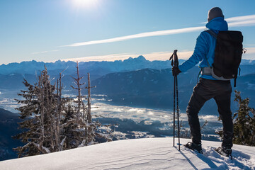 Hiker man with backpack stands on snowy summit of Tscheckelnock, Carinthia, Austria. Majestic...
