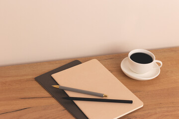 Cup of coffee and stationery on a wooden desk.