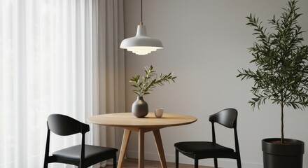 A small dining area with a round wooden table and two black chairs. A modern pendant lamp with soft white lighting hangs above the table