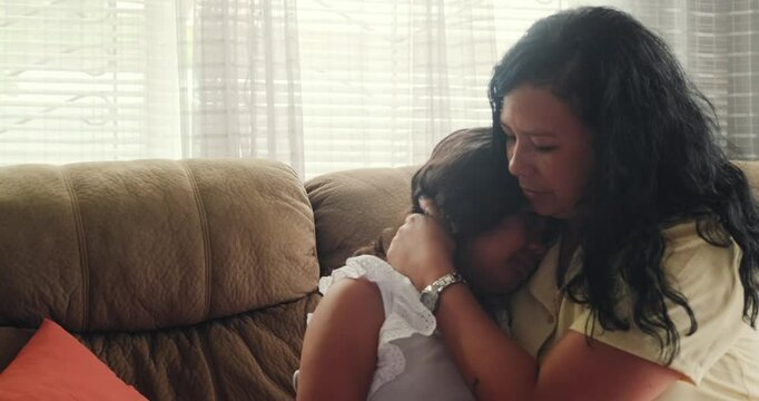Mom, daughter sitting on couch, Sad and emotional. Comforting and hugging crying child.