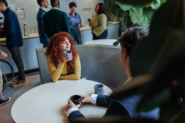 Colleagues enjoying coffee break in modern office cafeteria