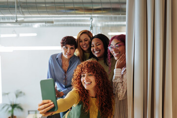 Group of diverse businesswomen taking a photo of themselves in modern office