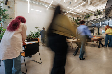 Busy designers moving around modern office with green plants