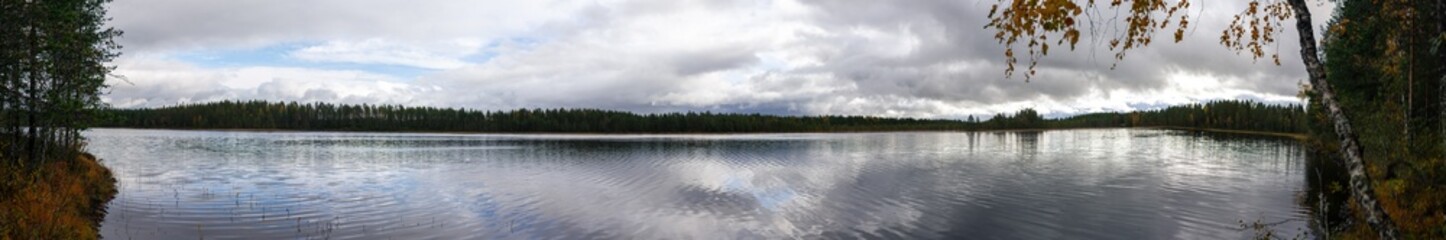 Panoramic View of Calm Lake Reflecting Cloudy Sky, Surrounded by Dense Autumn Forest