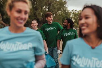 Volunteers in uniforms talking and carrying trash by the river