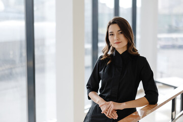 Fototapeta premium Young female doctor is standing in a hospital hall and looking at the camera