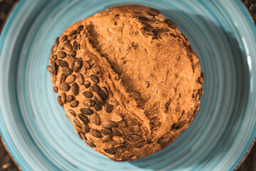 A loaf of rye bread on a turquoise or blue plate on a brown background. Close-up. Top view, Space for text