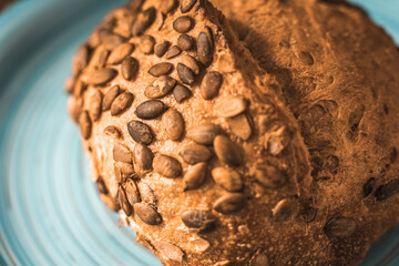 A loaf of rye bread on a turquoise or blue plate on a brown background. Close-up. Top view, Space for text